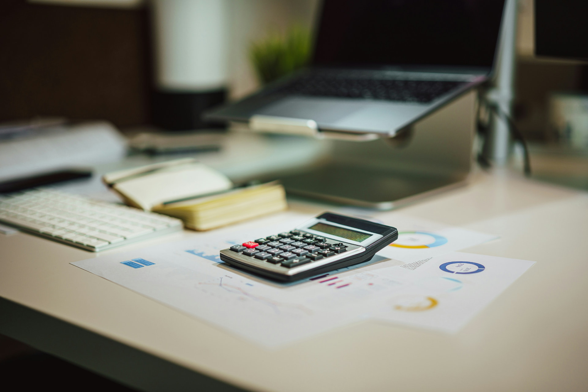 Desk with a calculator, laptop and financial reports