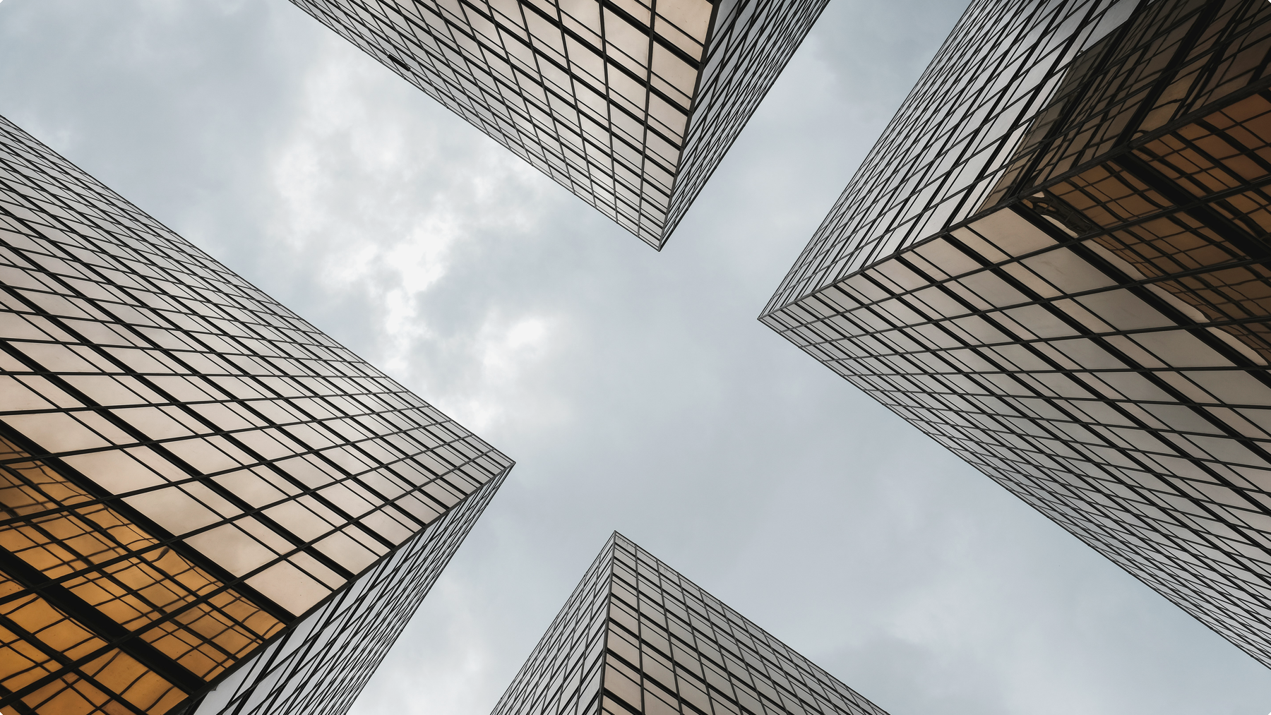 Glass office towers photographed from below against a pale sky